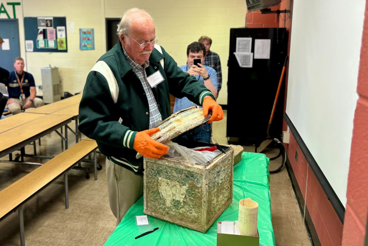 Jack Chiras, former history teacher, opens the time capsule during the ceremony